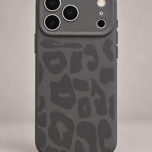 May include: A dark gray smartphone case featuring a matte finish and a tonal leopard print pattern. The case includes a raised camera module cutout with three circular lens openings and a flash cutout, with the Pouchora Studio logo at the bottom.