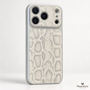 May include: A smartphone case with a silver frame and a textured off-white and grey snakeskin pattern on the back panel. The camera module area features a matching snakeskin inlay. The Pouchora Studio logo is visible in the bottom right corner.