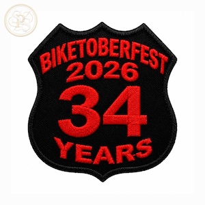 Puede incluir: Un parche bordado en forma de escudo con fondo negro y costuras rojas. El texto dice BIKETOBERFEST 2026, seguido del número grande 34 y la palabra YEARS debajo. El diseño presenta una fuente negrita clara y un borde de color negro.
