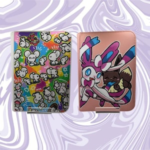 Puede incluir: Dos cubiertas rectangulares para carpetas de tarjetas. La cubierta izquierda presenta un fondo vibrante y multicolor con un patrón repetitivo de criaturas blancas parecidas a ratones. La derecha es rosa claro y muestra una ilustración de dos criaturas.