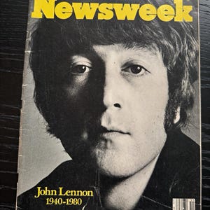 Pode incluir: Uma revista Newsweek vintage de 22 de dezembro de 1980, com um retrato em preto e branco de John Lennon na capa. O título amarelo está no topo e o texto John Lennon 1940-1980 está impresso em amarelo no canto inferior esquerdo.