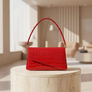 May include: A vibrant red handbag featuring a textured crocodile-embossed pattern. The bag has a structured rectangular shape with a single arched handle attached by gold-toned metal hardware and a diagonal flap closure on the front.