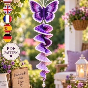 May include: A hanging crochet decoration featuring a purple butterfly at the top with a long, spiraling, ombre-colored tail that transitions from deep violet to light lavender. The piece is finished with a single white bead at the bottom.
