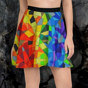 May include: A skater skirt with a vibrant, geometric stained-glass pattern in shades of red, orange, yellow, green, blue, and purple. The skirt has a black waistband and is worn with black sneakers.