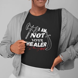 May include: Black t-shirt with a white graphic design of crossed axes and a sword with the text "I AM NOT YOUR HEALER".