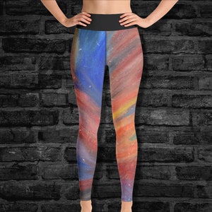 May include: A pair of colourful leggings with a watercolour-like design featuring shades of blue, red, orange, and yellow. The leggings have a black waistband.