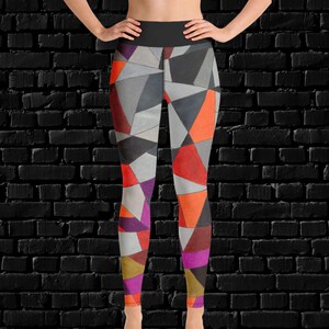 Puede incluir: Leggins negros con un patrón geométrico en tonos de gris, naranja, rojo, morado y dorado.
