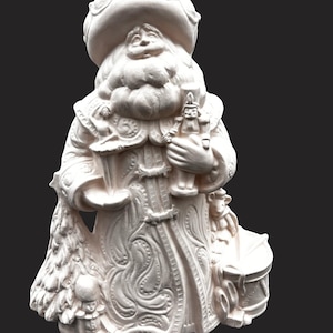 May include: An unpainted ceramic figurine of a bearded figure wearing a large hat and ornate robe. The figure holds a small ballerina and a nutcracker, with a Christmas tree, a toy soldier, and a drum positioned at the base of the robe.