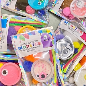 May include: Clear plastic bags filled with monster-themed craft kits. Each kit includes colorful pipe cleaners, pom-poms, and a container with monster features. The bags have a label that says "Build Your Own Birthday Monster".