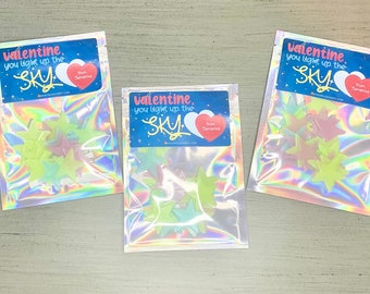 May include: Three iridescent pouches each containing star-shaped decorations in shades of green, pink, and yellow. Each pouch has a label that reads "Valentine, you light up the SKY" with a heart and the name "Samantha".