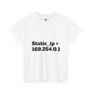 May include: A white short-sleeved t-shirt featuring the black text Static_ip = 169.254.0.1 printed on the center of the chest. The garment has a crew neckline and a standard fit, with a small blue circular logo visible on the inner neck label area.