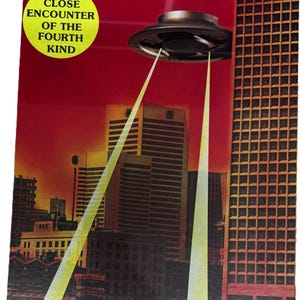 Puede incluir: Una caja de juego de mesa rectangular titulada UFO con el subtítulo A CLOSE ENCOUNTER OF THE FOURTH KIND. La portada muestra un platillo volante metálico oscuro sobre el horizonte de una ciudad al atardecer, emitiendo dos rayos de luz amarillos.