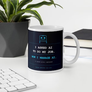 May include: A white ceramic mug featuring a dark blue graphic design with a light blue robot icon. The text reads: I ASKED AI TO DO MY JOB. NOW I MANAGE AI. // career pivot: unplanned. STATUS: EMPLOYED (for now). The mug has a standard handle.