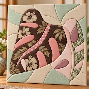 May include: A square fabric wall art piece featuring a patchwork design of curved segments. The composition includes dark brown fabric with hibiscus and leaf prints, light pink and mauve solid panels, and pale green sections with wave patterns.