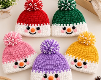 May include: Five crocheted beanies featuring snowman faces with black button eyes, orange noses, and pink cheeks. Each hat has a white brim and a matching colored pom-pom on top in red, green, pink, purple, and yellow yarn colors.