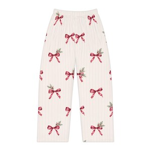 May include: Off-white lounge pants featuring a repeating pattern of red ribbon bows accented with small green pine sprigs and tiny red berries. The pants have a high elastic waistband and a straight-leg cut with subtle vertical pinstripes.