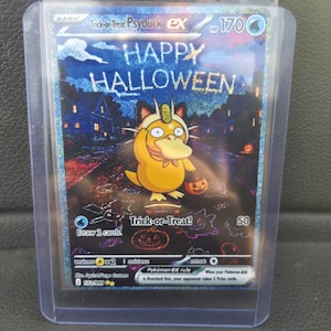 May include: A holographic Trick-or-Treat Psyduck ex Pokémon trading card featuring the character in a cat costume holding a pumpkin bucket. The card displays the text HAPPY HALLOWEEN, 170 HP, and Trick-or-Treat, enclosed in a clear plastic sleeve.