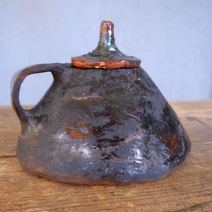 Puede incluir: Una taza de cerámica blanca con un asa negra y el texto "But First, Coffee" en negro, en negrita. La taza está sobre una superficie blanca.