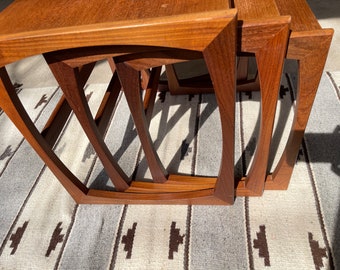 Puede incluir: Un conjunto de tres mesas nido de madera con un diseño moderno de mediados de siglo. Las mesas están hechas de madera oscura y tienen una forma curva y geométrica.