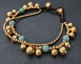 May include: A double-strand ankle bracelet with gold-toned bells and green beads.
