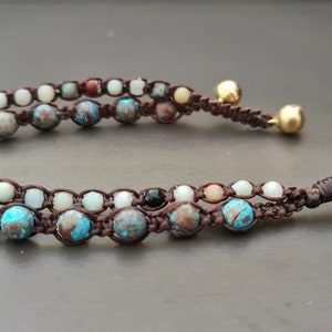 May include: A brown leather bracelet with two rows of colorful beads, including turquoise, white, and brown. The bracelet has gold-colored metal accents.