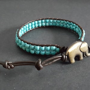 May include: A turquoise beaded bracelet with a brown leather strap and an elephant charm.