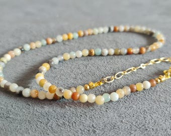 May include: A delicate necklace made with small, multi-colored beads. The necklace is made with a gold chain and clasp.