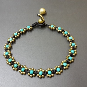 May include: A turquoise and gold beaded anklet with a black cord and a small gold bell charm.