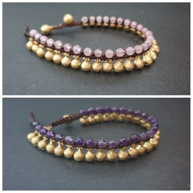 May include: Two anklets with gold beads and a brown cord. One anklet has pink beads and the other has purple beads.