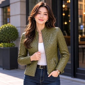 May include: An olive green jacket with a textured hexagonal pattern, a stand-up collar, and a front zip fastening. The jacket is worn over a white top and dark blue jeans with a black belt. The design includes long sleeves and side pockets.