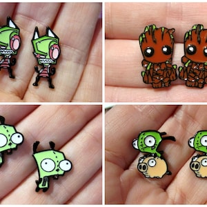 May include: A set of four pairs of cartoon character earrings. The first pair features Invader Zim, the second pair features Groot, the third pair features Invader Zim, and the fourth pair features Invader Zim riding a pig.
