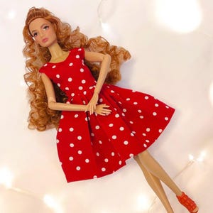 May include: A red dress with white polka dots. The dress has a sleeveless design and a fitted bodice. The skirt is full and flowing.