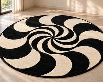 Op de afbeelding: Een rond vloerkleed met een contrastrijk patroon in zwart en gebroken wit. Het ontwerp bestaat uit gebogen, stralende segmenten die vanuit het midden naar buiten spiralen, wat een dynamisch, herhalend vortex-effect over het oppervlak creëert.