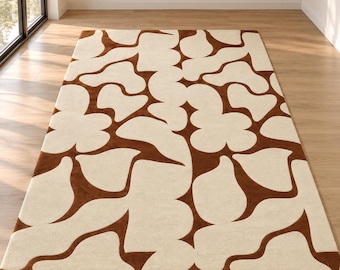 Op de afbeelding: Een rechthoekig vloerkleed met een herhalend, grootschalig abstract patroon in donkerbruin en crème. Het ontwerp bestaat uit onderling verbonden, vloeiende, organische vormen die een gedurfd, grafisch effect met hoog contrast creëren.
