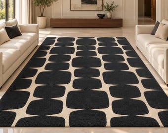 Puede incluir: Una alfombra rectangular con un patrón repetitivo de grandes cuadrados negros redondeados dispuestos en una cuadrícula sobre un fondo de color crema. El diseño crea un motivo geométrico de alto contraste que cubre toda la superficie.