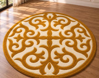 Op de afbeelding: Een rond vloerkleed met een opvallend patroon in mosterdgeel en crème. Het ontwerp bestaat uit symmetrische, wervelende en onderling verbonden motieven die vanuit het midden naar de buitenrand van de ronde vloerbedekking uitstralen.