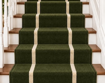 Op de afbeelding: Een trap met een donker bosgroene tapijtloper met een enkele verticale crèmekleurige streep in het midden. Het tapijt is over houten treden geïnstalleerd, geflankeerd door witte balusters en een houten leuning aan de linkerzijde.