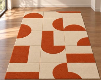 Puede incluir: Una alfombra rectangular con un patrón geométrico de formas de color naranja quemado sobre un fondo crema. El diseño consiste en varios semicírculos, rectángulos y bloques en forma de L dispuestos en una cuadrícula por toda la superficie.
