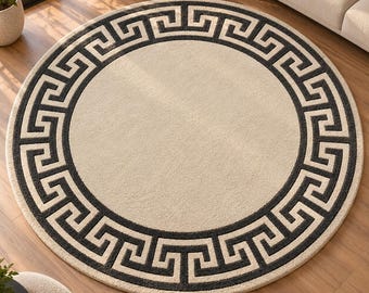 Op de afbeelding: Een rond vloerkleed met een effen crèmekleurig midden, omringd door een brede, donker antracietkleurige rand. De rand is versierd met een doorlopend, herhalend geometrisch Grieks sleutelpatroon in een contrasterende crèmekleur.
