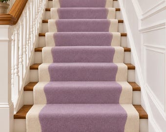 Op de afbeelding: Een trap met een centrale lavendelkleurige loper met crèmekleurige randen. De treden zijn van hout met witte stootborden, geflankeerd door een witte houten trapleuning met een gepolijste houten handgreep en witte muren met lambrisering.