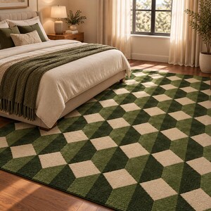 Puede incluir: Una alfombra rectangular con un patr&oacute;n geom&eacute;trico de cubos tridimensionales en tonos verde bosque, verde oliva y crema. La alfombra est&aacute; colocada sobre un suelo de madera, extendi&eacute;ndose parcialmente debajo de una cama con una manta verde.