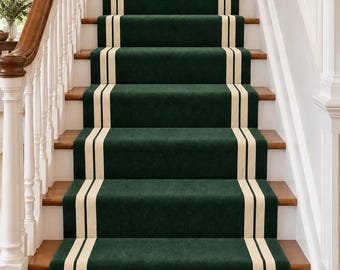 Op de afbeelding: Een donkergroene traploper met twee parallelle crèmekleurige strepen die verticaal door het midden lopen. De loper is geïnstalleerd op een houten trap met witte balusters en een houten leuning aan de linkerzijde.