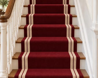 Op de afbeelding: Een dieprode traploper geïnstalleerd op een trap, voorzien van twee parallelle beige strepen die verticaal over het midden van elke trede lopen. De loper bedekt het middelste gedeelte van de houten treden, omlijst door witte leuningen.