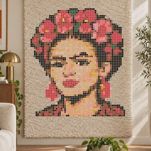 Può includere: Un arazzo rettangolare che presenta un ritratto pixelato di una persona con una corona di fiori. L'opera è realizzata in tonalità di rosa, giallo e nero su uno sfondo tessile color crema, a pelo lungo e shaggy, con un bastone in legno.