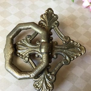 Peut inclure: Poign&eacute;e de tiroir antique en laiton orn&eacute;, avec une poign&eacute;e octogonale d&eacute;corative et un motif floral. La quincaillerie est de couleur laiton vieilli et chaleureux, id&eacute;ale pour la restauration de meubles anciens.