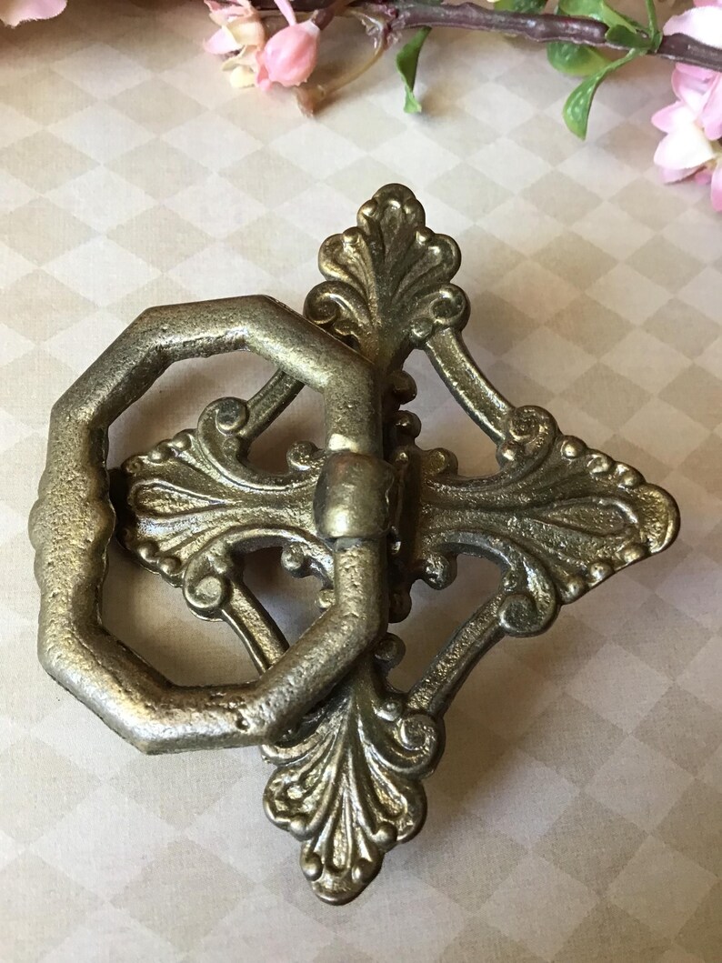 Peut inclure: Poign&eacute;e de tiroir antique en laiton orn&eacute;, avec une poign&eacute;e octogonale d&eacute;corative et un motif floral. La quincaillerie est de couleur laiton vieilli et chaleureux, id&eacute;ale pour la restauration de meubles anciens.