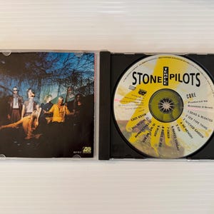 May include: A Stone Temple Pilots "Core" CD in a black jewel case. The CD features a yellow and black design with song titles. The case insert shows the band in a dark, outdoor setting.