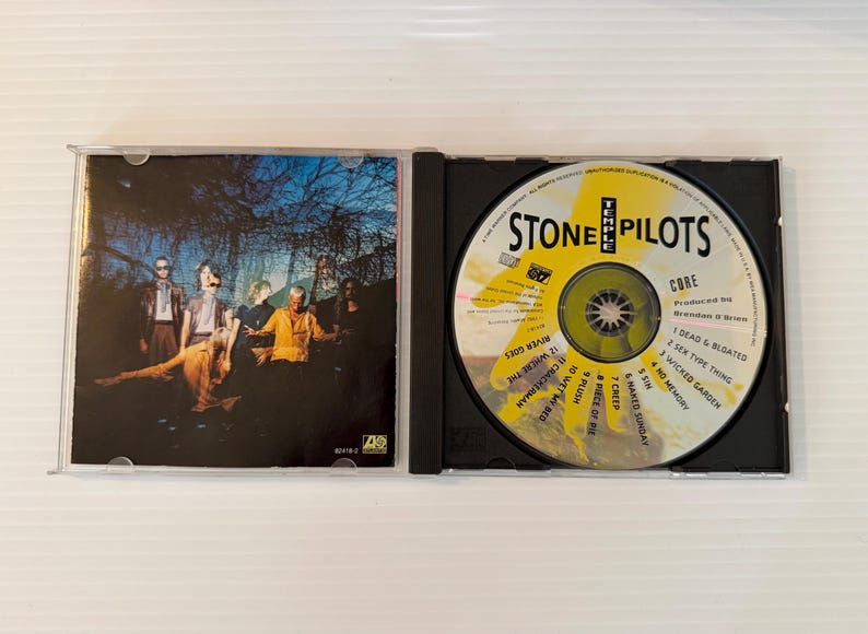 May include: A Stone Temple Pilots "Core" CD in a black jewel case. The CD features a yellow and black design with song titles. The case insert shows the band in a dark, outdoor setting.