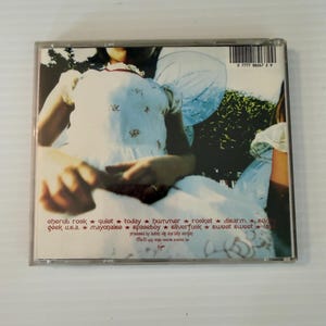 May include: A compact disc case featuring album art with a person in a white dress with angel wings. The tracklist includes "eherub rock", "quiet", "today", "hummer", "rocket", "disarm", "geek u.s.a.", "mayonaise", "spaceboy", "silverfuck", "sweet sweet", and "la".