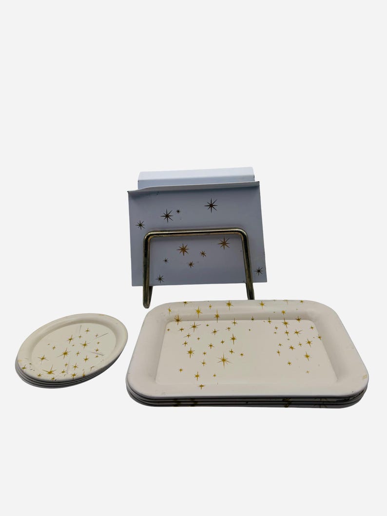 May include: A set of vintage serving trays and a notepad holder. The trays are off-white with a gold starburst pattern. The notepad holder has a matching design. The metal stand is a warm, brassy color.